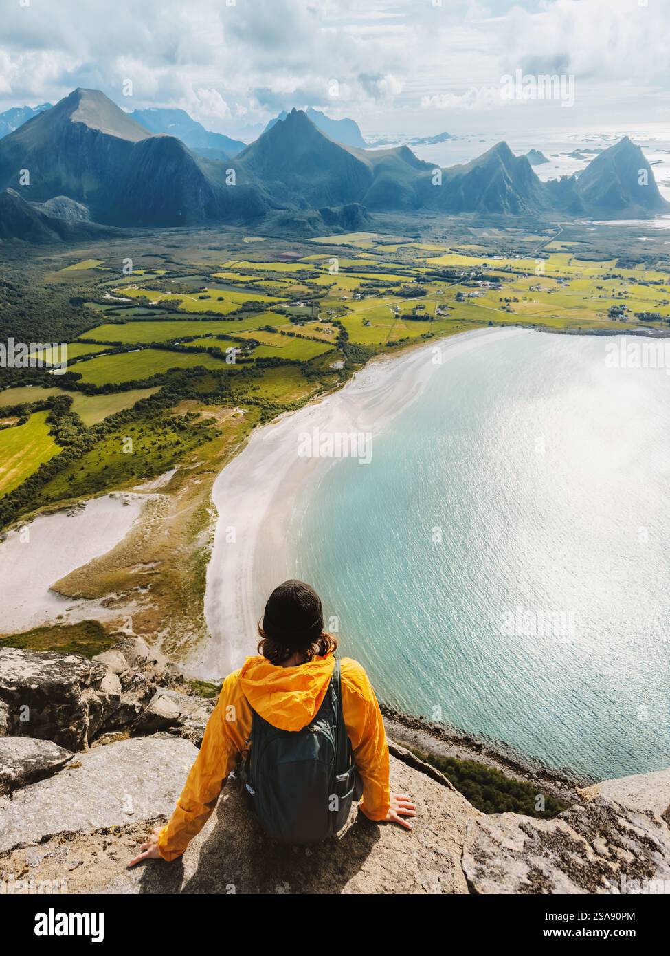 Homme voyageur assis sur la falaise de montagne au-dessus de la mer en Norvège, randonnée touristique solo en plein air profitant de la vue sur la plage de Bosanden, vacances d'été actives en bonne santé Banque D'Images