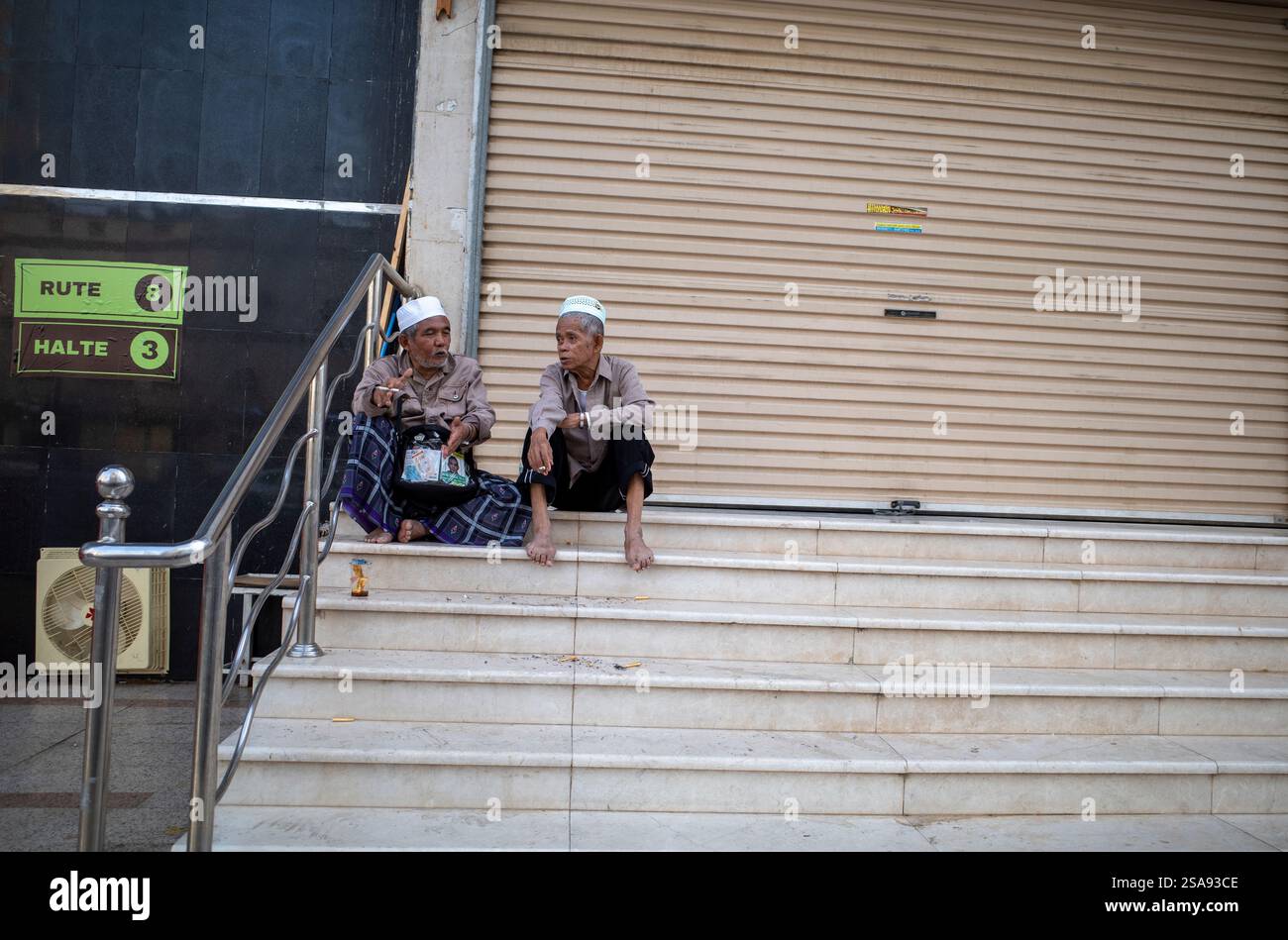 La Mecque, Arabie Saoudite - 13 juin 2024 : deux vieux pèlerins du Hadj et de l'Oumrah venus d'Indonésie assis devant un hôtel à Makkah, Arabie Saoudite. Hajj 2024 Banque D'Images