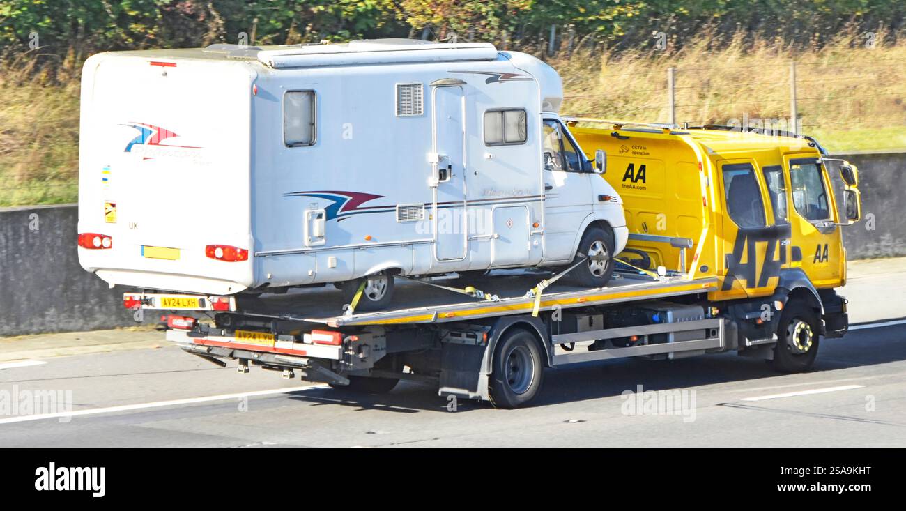 Jaune AA camion de récupération de secours à plateau transportant un camping-car conduisant la route de l'autoroute M25 route orbitale de Londres dans le comté d'Essex Angleterre Banque D'Images