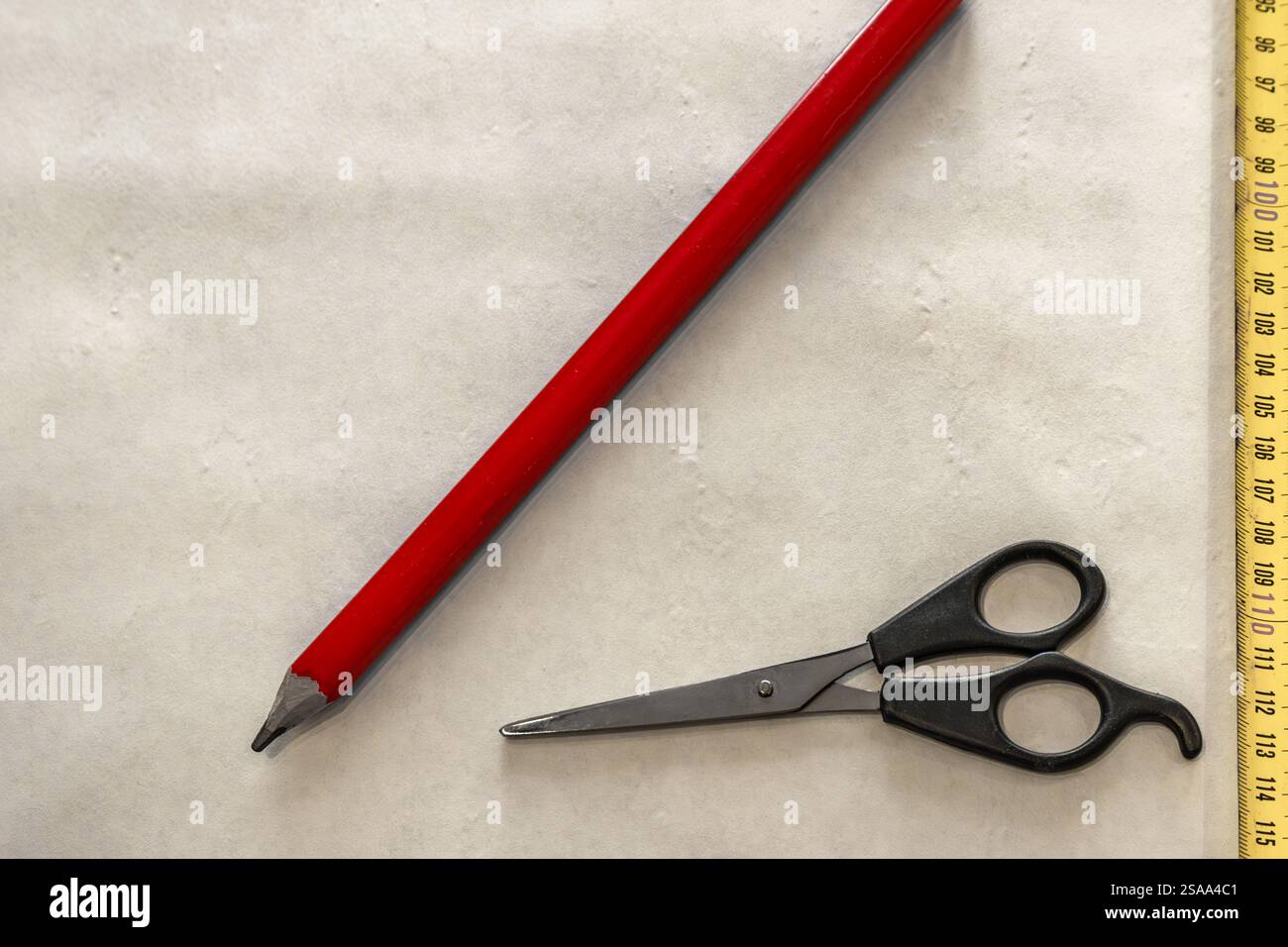 Couper le papier peint avant de le coller au mur, ciseaux, ruban à mesurer et crayon sur la table, couper le papier peint à la taille Banque D'Images