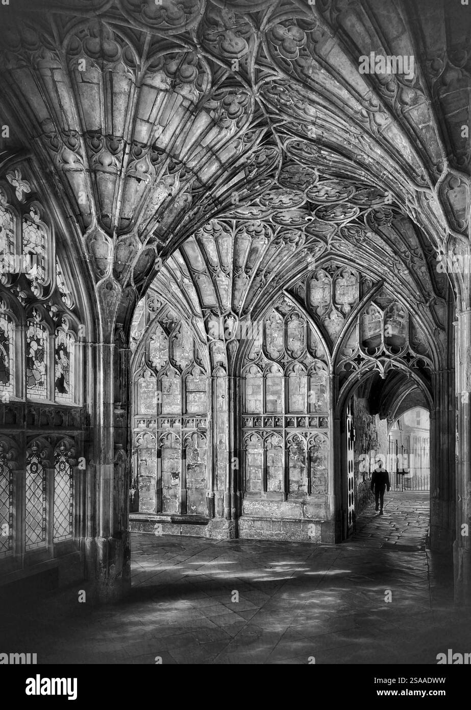 Un enfant silhouette marche dans un passage attaché aux cloîtres voûtés en éventail de la cathédrale de Gloucester. Lieu de tournage de Harry Potter's Poudlard. Banque D'Images