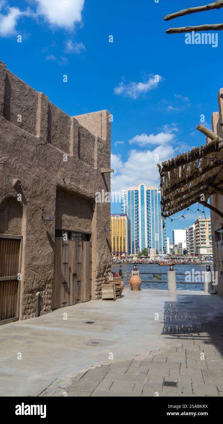 Rue de la vieille ville de Dubaï Al Seef Khor dans le quartier Al Fahidi, Émirats arabes Unis. Promenade au bord de l'eau le long de la rive de Dubai Creek. Image verticale. Banque D'Images