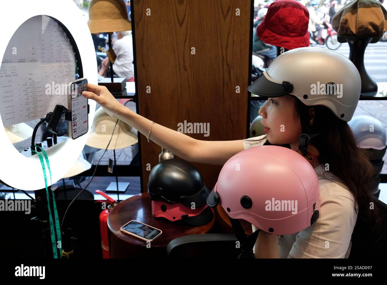 Jeune femme se filmant pour faire de la publicité pour ses produits en vente sur les réseaux sociaux. Ho Chi Minh ville. Vietnam. Banque D'Images