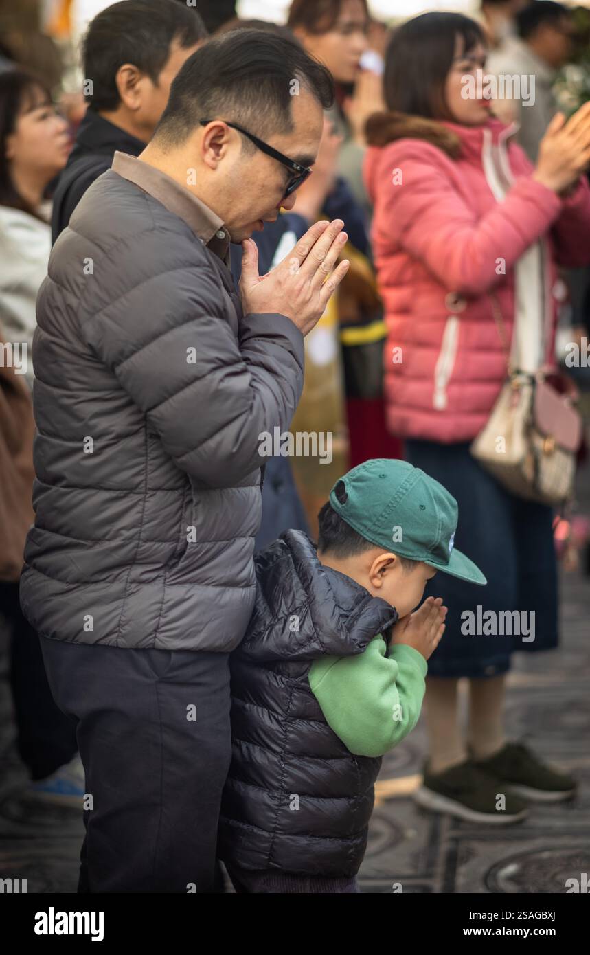 Un père et son jeune fils prient à l'ancienne pagode bouddhiste Tran Quoc le premier jour du nouvel an lunaire, ou Têt, à Hanoi, au Vietnam. Banque D'Images