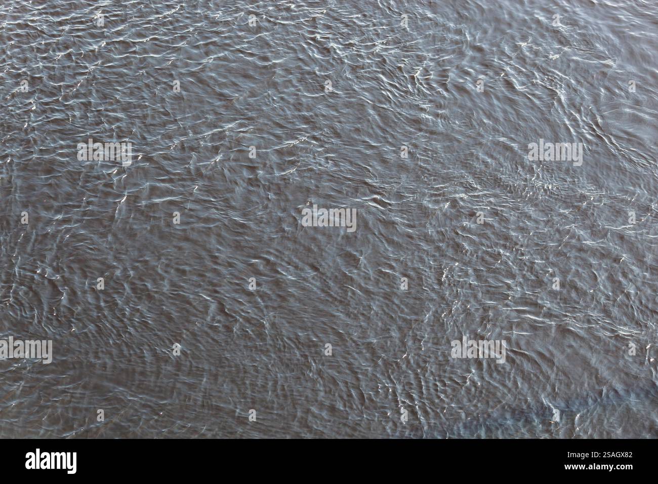 Texture de l'eau avec de légères ondulations sur la surface. Eau calme avec de petites vagues et des reflets lumineux créant un effet visuel intéressant. Arrière-plan Banque D'Images