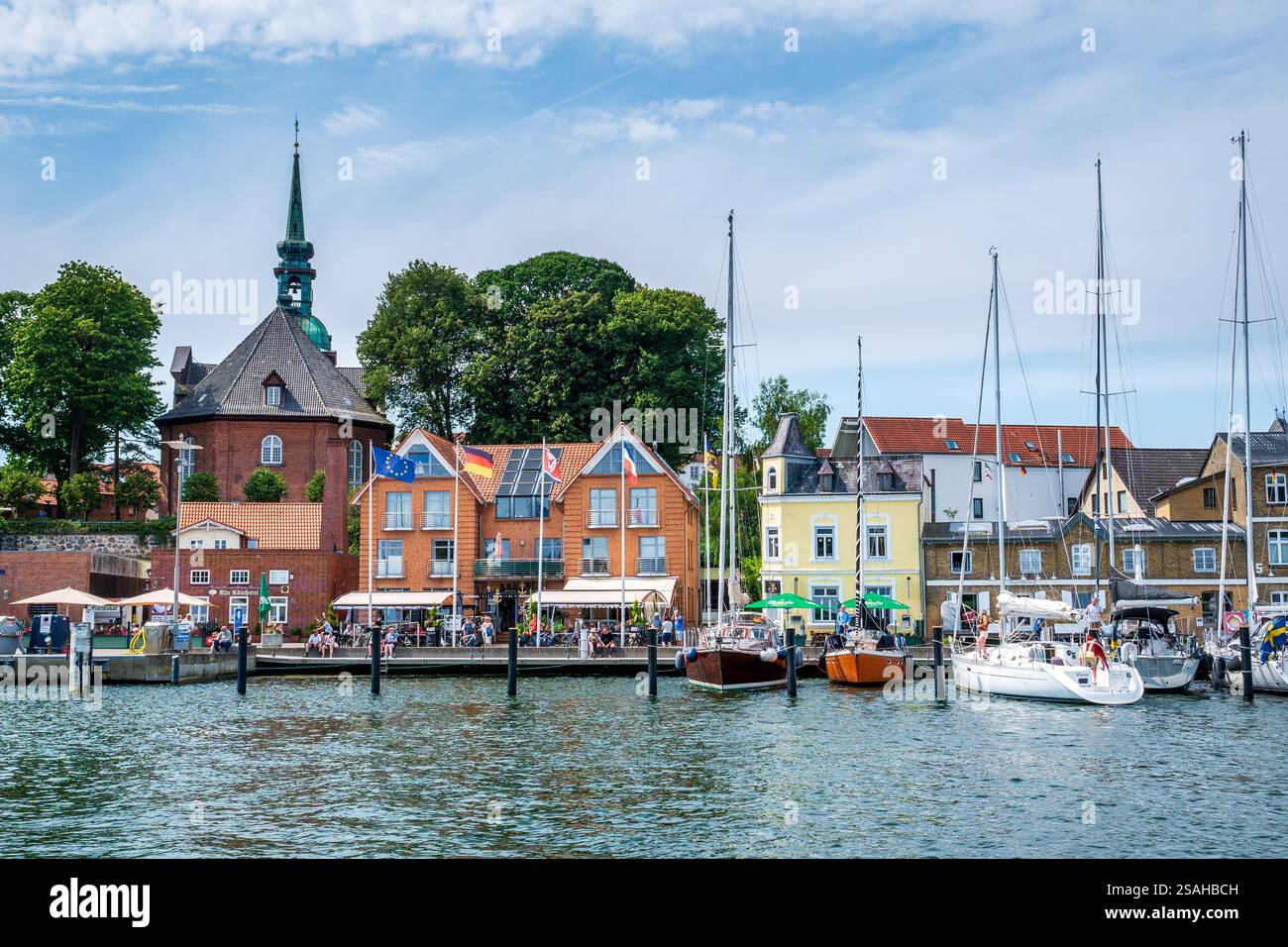 Voiliers et personnes appréciant l'été sur le quai am Hafen dans la vieille ville de Kappeln, Schleswig-Holstein, Allemagne Banque D'Images