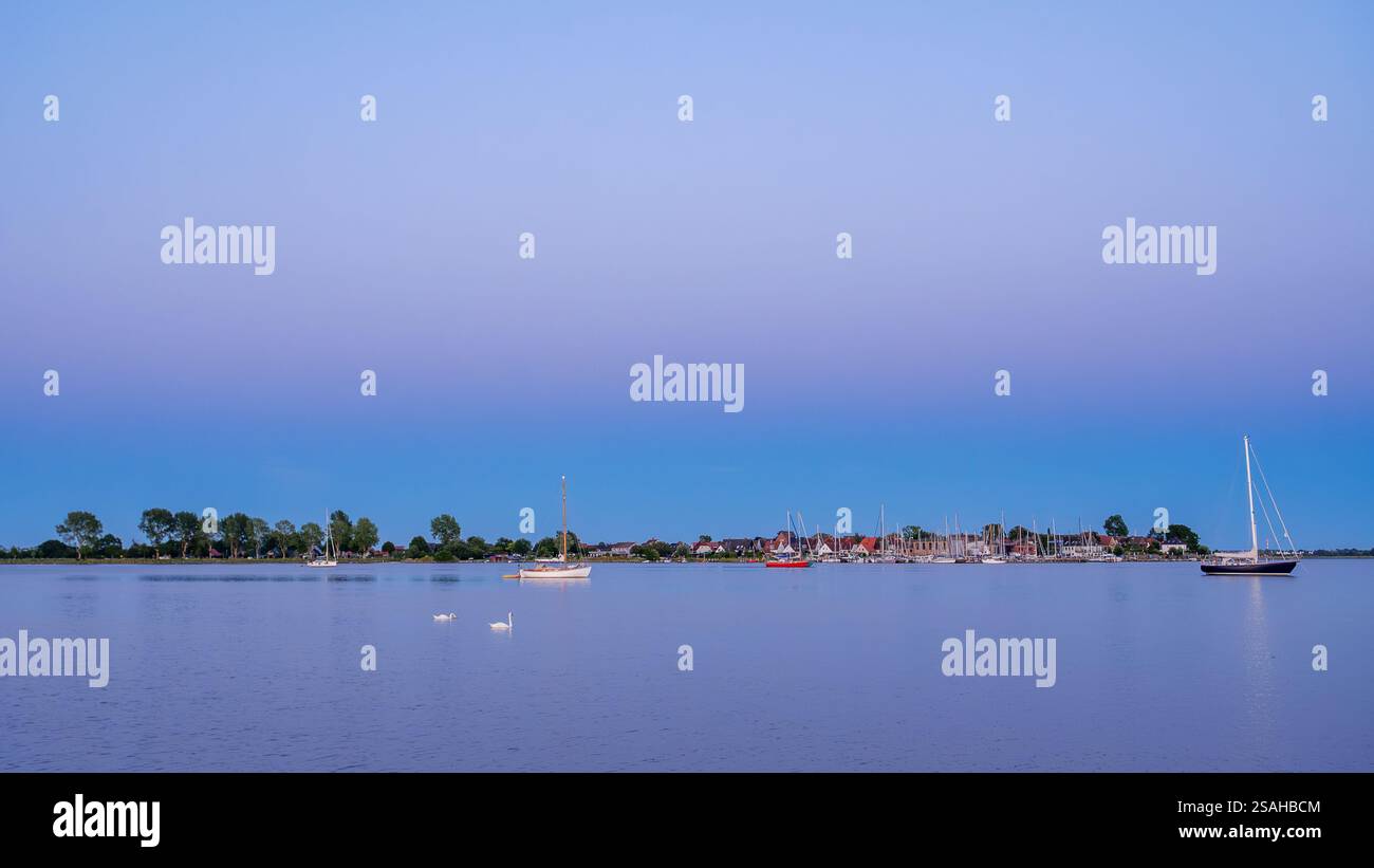 Côte de Maasholm avec port et voiliers amarrés à Wormshöfter Noor à l'heure bleue, Schlei Fjord, Schleswig-Holstein, Allemagne Banque D'Images