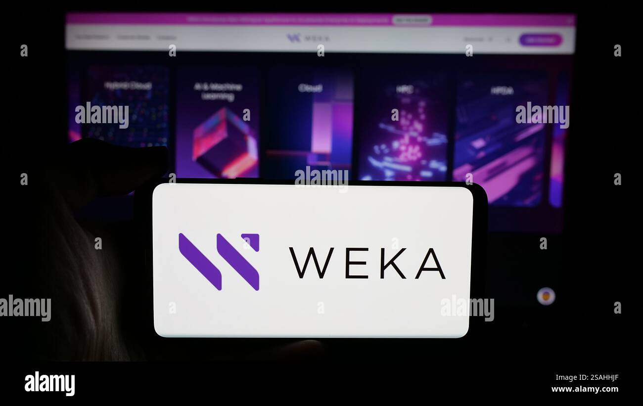 Dans cette illustration photo, une personne tient un téléphone portable avec le logo de la société de plate-forme de données américaine WekaIO Inc sur l'écran devant la page Web de l'entreprise. Banque D'Images