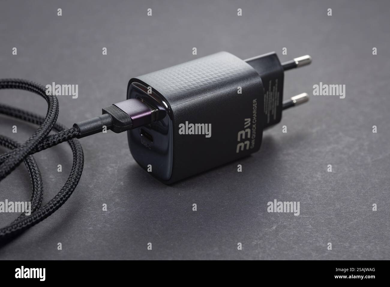 Chargeur secteur de téléphone noir et câble USB sur fond sombre. Banque D'Images