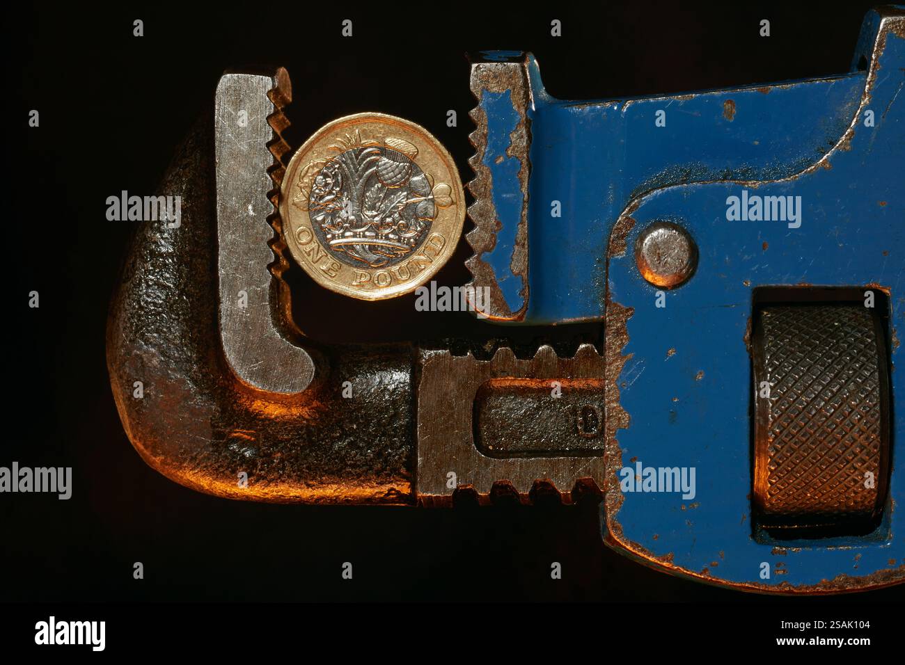 Une pièce britannique d'une livre sous pression dans la poignée d'une clé. Sur un fond noir avec une lumière chaude sous la clé donnant l'impression de chaleur. Banque D'Images