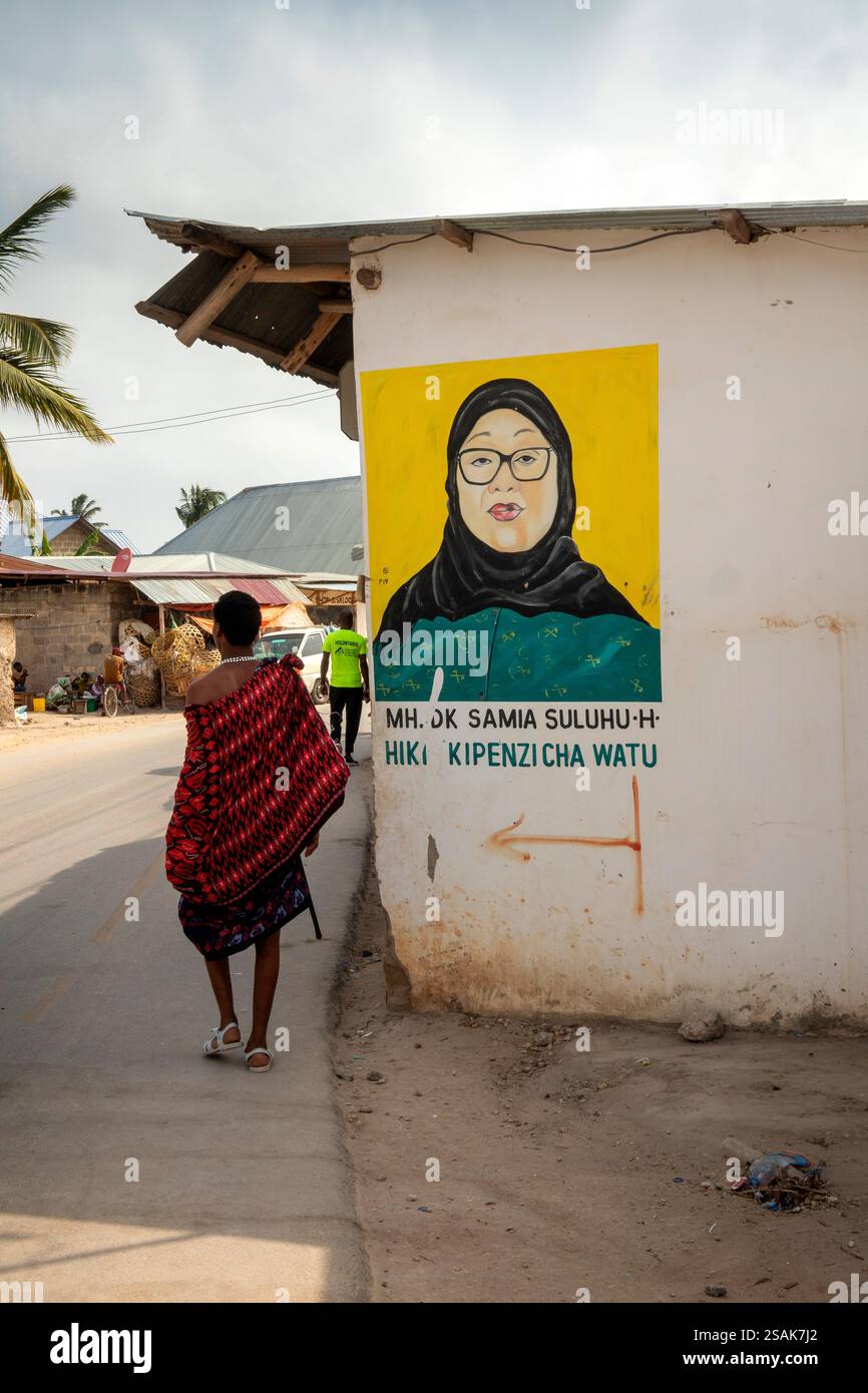 Afrique Tanzanie, Zanzibar, Nungwi, Masaï homme marchant devant un portrait mural féminin Banque D'Images Afrique Tanzanie, Zanzibar, Nungwi, Masaï homme marchant devant un portrait mural féminin Banque D'Images