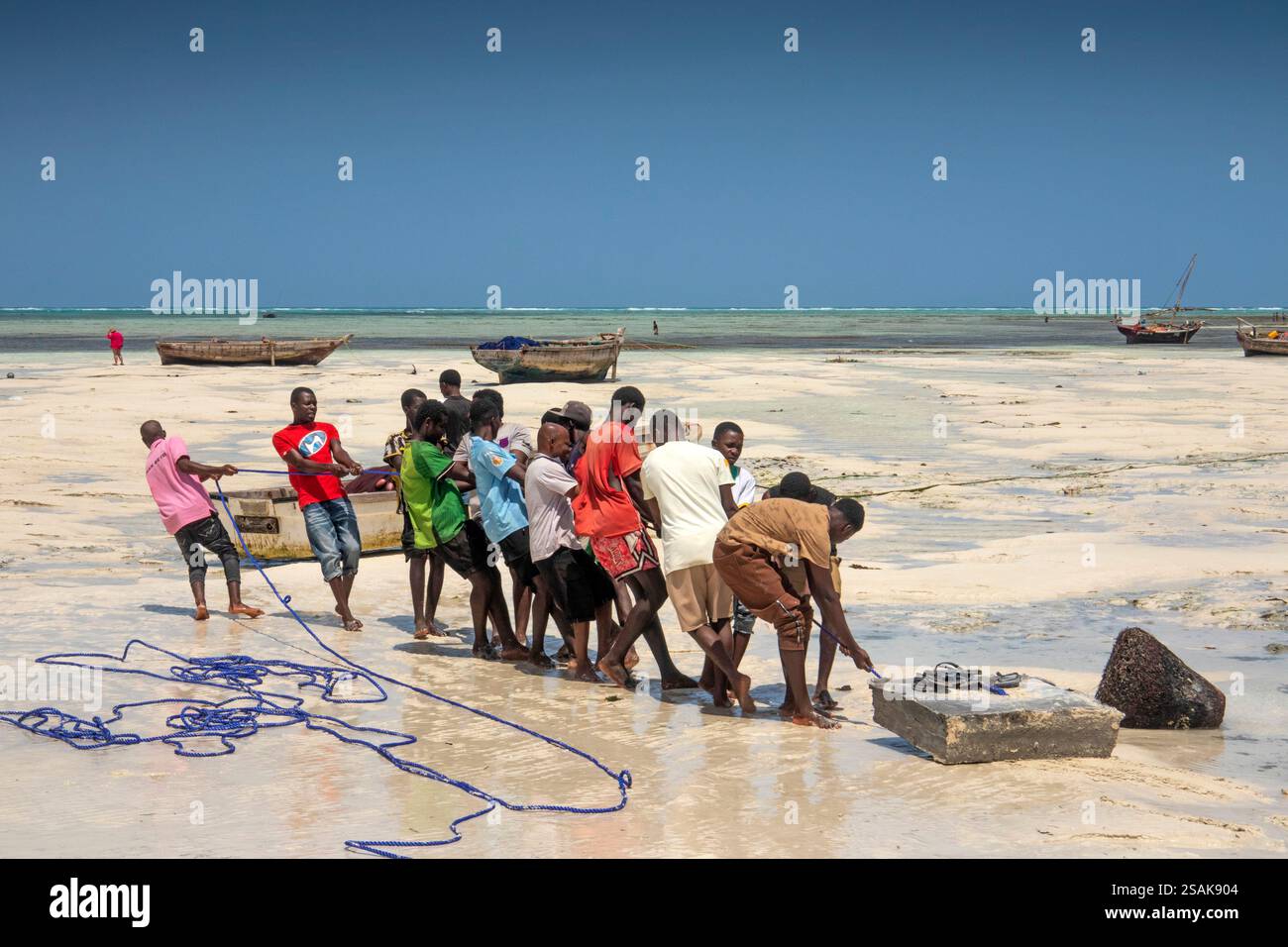 Afrique Tanzanie, Zanzibar, Nungwi, plage, hommes traînant de lourds blocs de béton vers la mer pour former un amarrage Banque D'Images