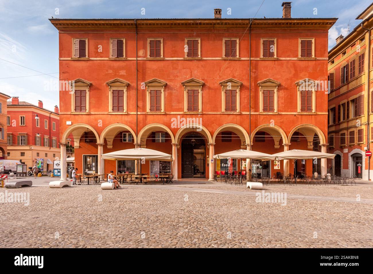 Bâtiment historique Orange avec portique à arcades dans une place pavée de Modène, Italie Banque D'Images