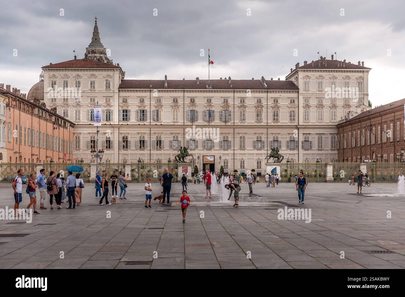 Vue de Piazza Castello à Turin, Piémont, Italie, avec le Palais Royal et les gens marchant à travers la place historique sous ciel nuageux. Banque D'Images