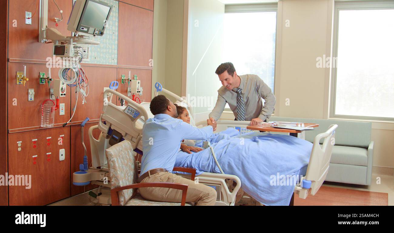 Médecin masculin rencontre et serrant la main avec le père visitant la fille dans le lit de l'hôpital Banque D'Images