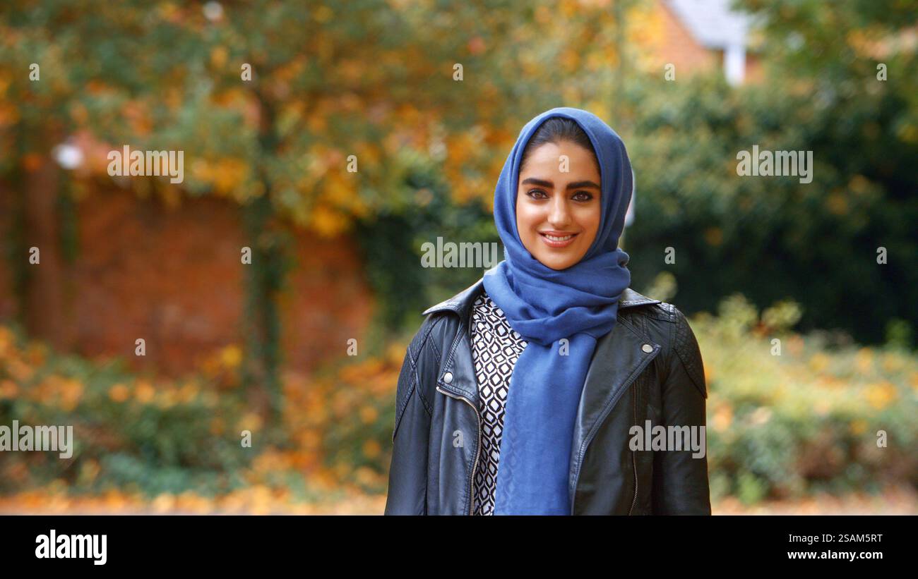 Tête et épaules Portrait de sourire jeune femme musulmane britannique portant le Hijab dans Autumn Park Banque D'Images