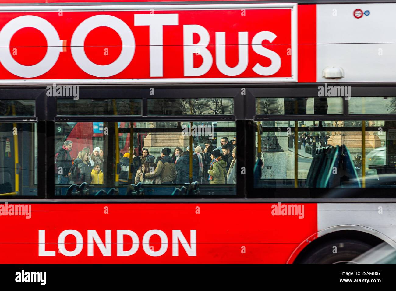 TOOT BUS passant devant les touristes londoniens. La foule de personnes sont regroupées autour de leur Guide. Photo intéressante comme vous voyez les gens à travers le Bus. Banque D'Images