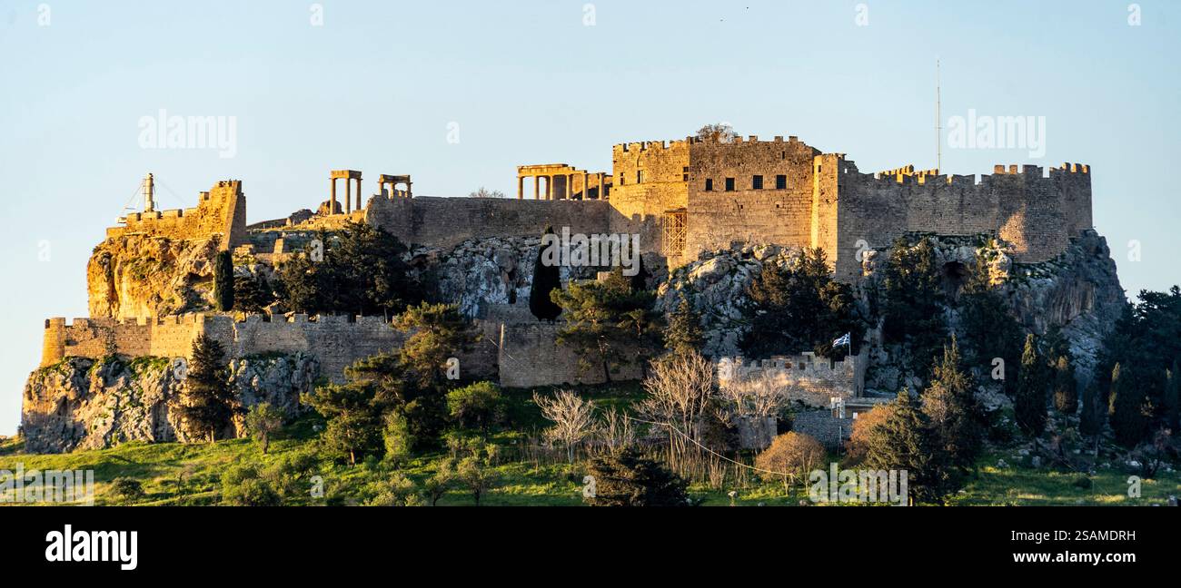 Une vue panoramique sur un château historique perché sur une colline rocheuse, entouré de verdure luxuriante et d'arbres. Le château présente d'anciens murs de pierre, des tours, Banque D'Images