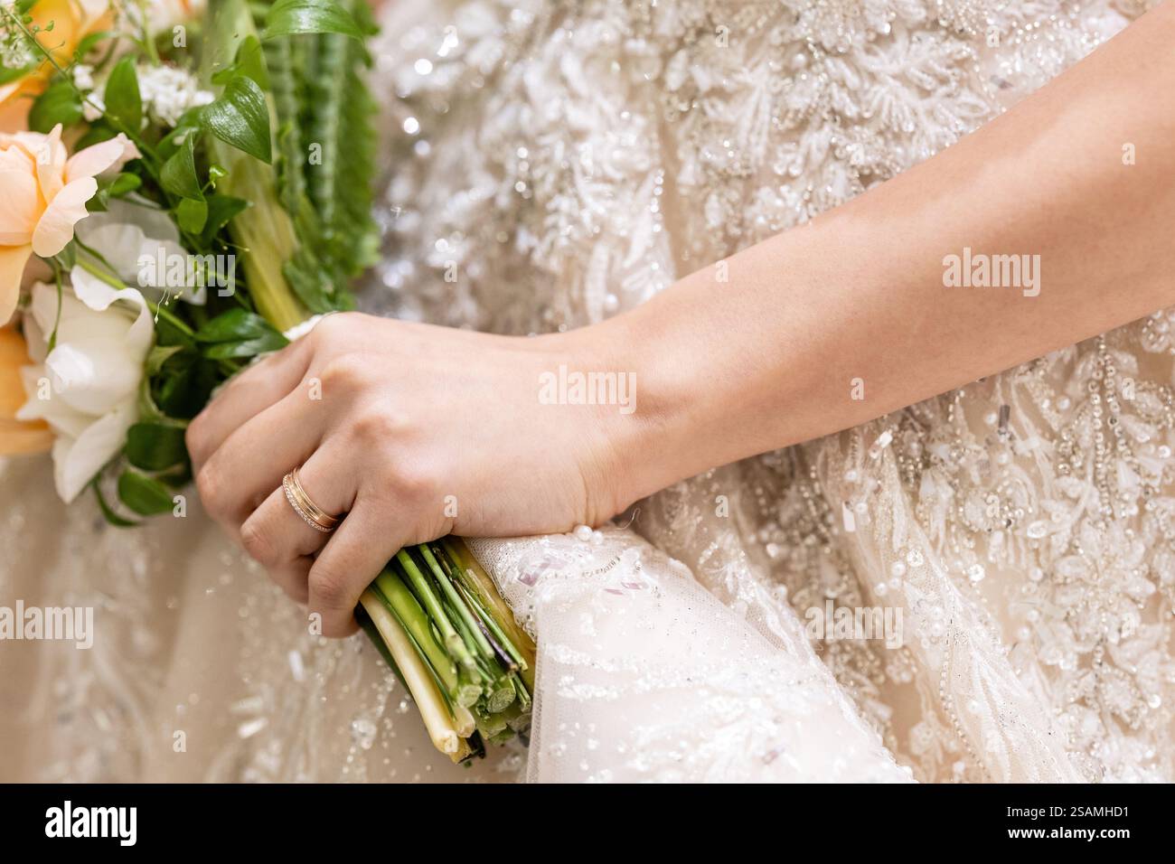 La femme tient un bouquet de fleurs et une bague. La bague est sur son doigt Banque D'Images