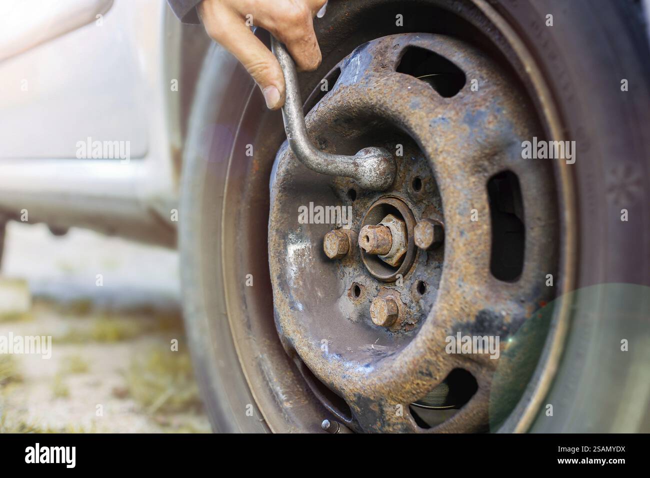 Personne utilisant une clé sur une roue de voiture rouillée, en se concentrant sur la réparation Banque D'Images