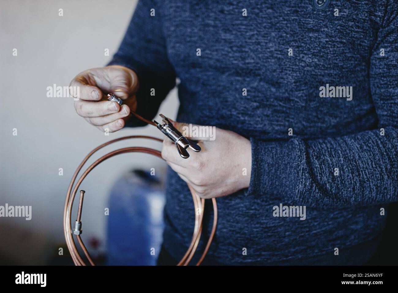 Personne tenant une bobine de cuivre et un outil, indiquant une tâche mécanique ou de réparation Banque D'Images