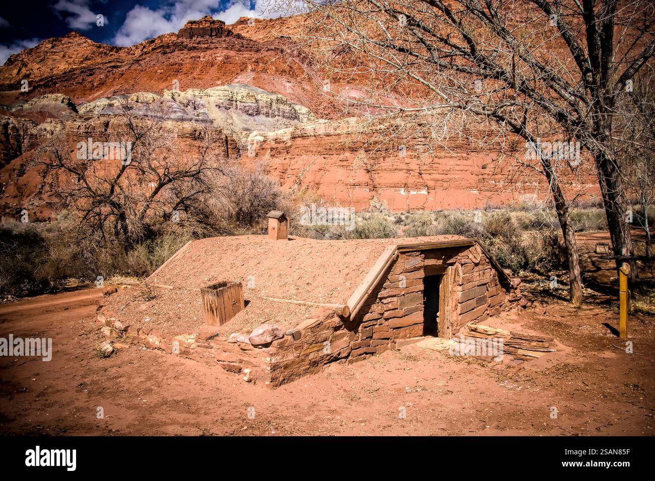 Une petite maison avec un toit en pierre se trouve dans un désert. La maison est entourée d'arbres et de rochers Banque D'Images