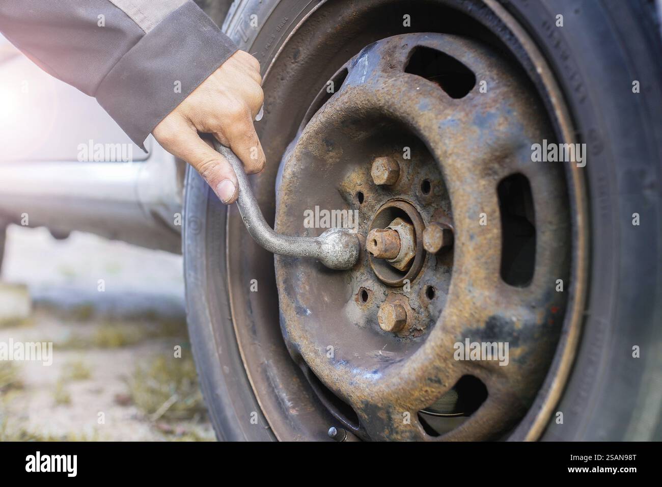 Tâche d'entretien sur une roue de voiture avec une clé et des gants, montrant de la rouille Banque D'Images