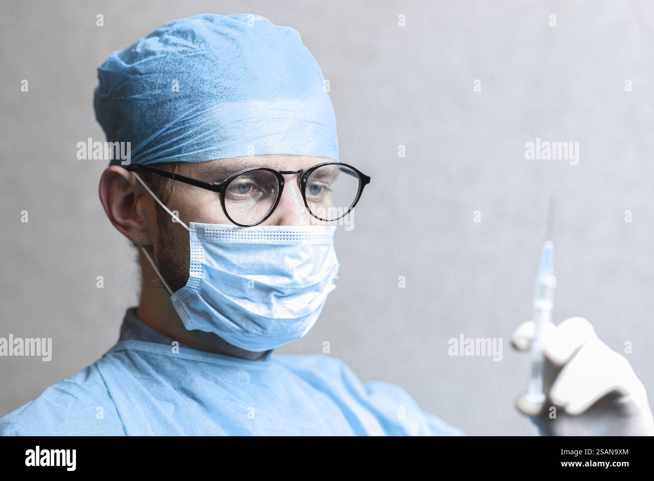 Professionnel de la santé portant des lunettes et un masque tenant une seringue Banque D'Images