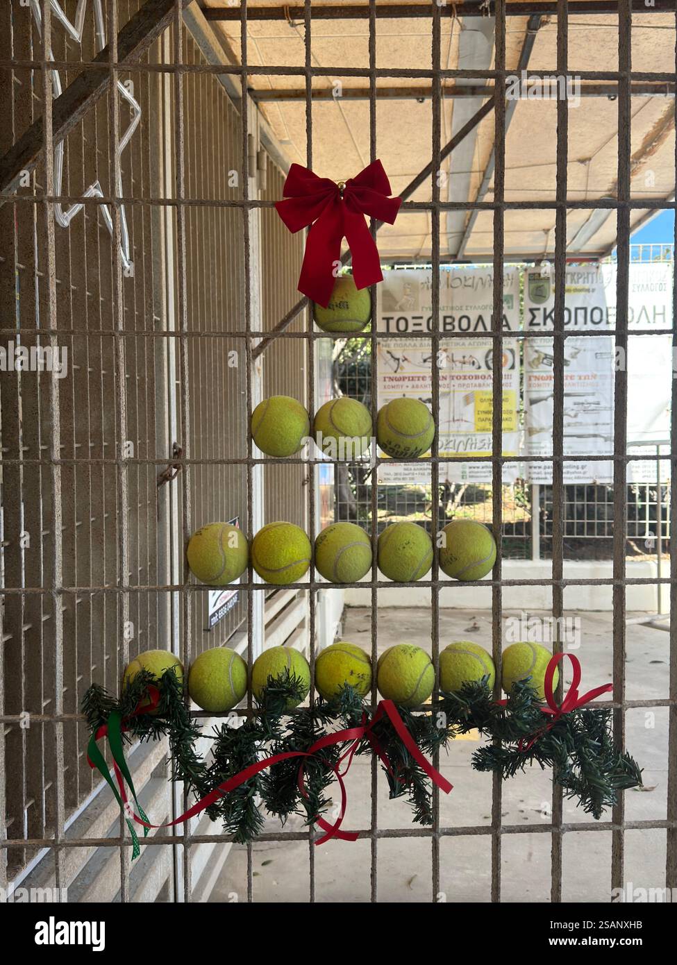 Un arbre de Noël fait de balles de tennis à la porte du stade Pankrition avec un arc rouge festif sur le dessus et une étoile à côté de lui -esprit de Noël athlétique Banque D'Images