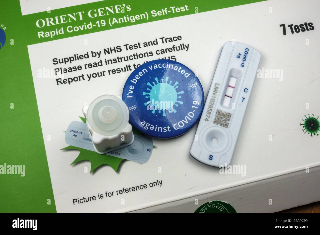 Ironie : un véritable kit de test positif COVID-19 utilisant un kit de test à flux latéral Orient Gene et un badge « J'ai été vacciné », Londres, Royaume-Uni. Banque D'Images
