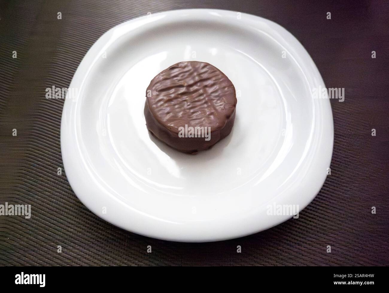 Alfajor recouvert de chocolat sur plaque blanche Banque D'Images