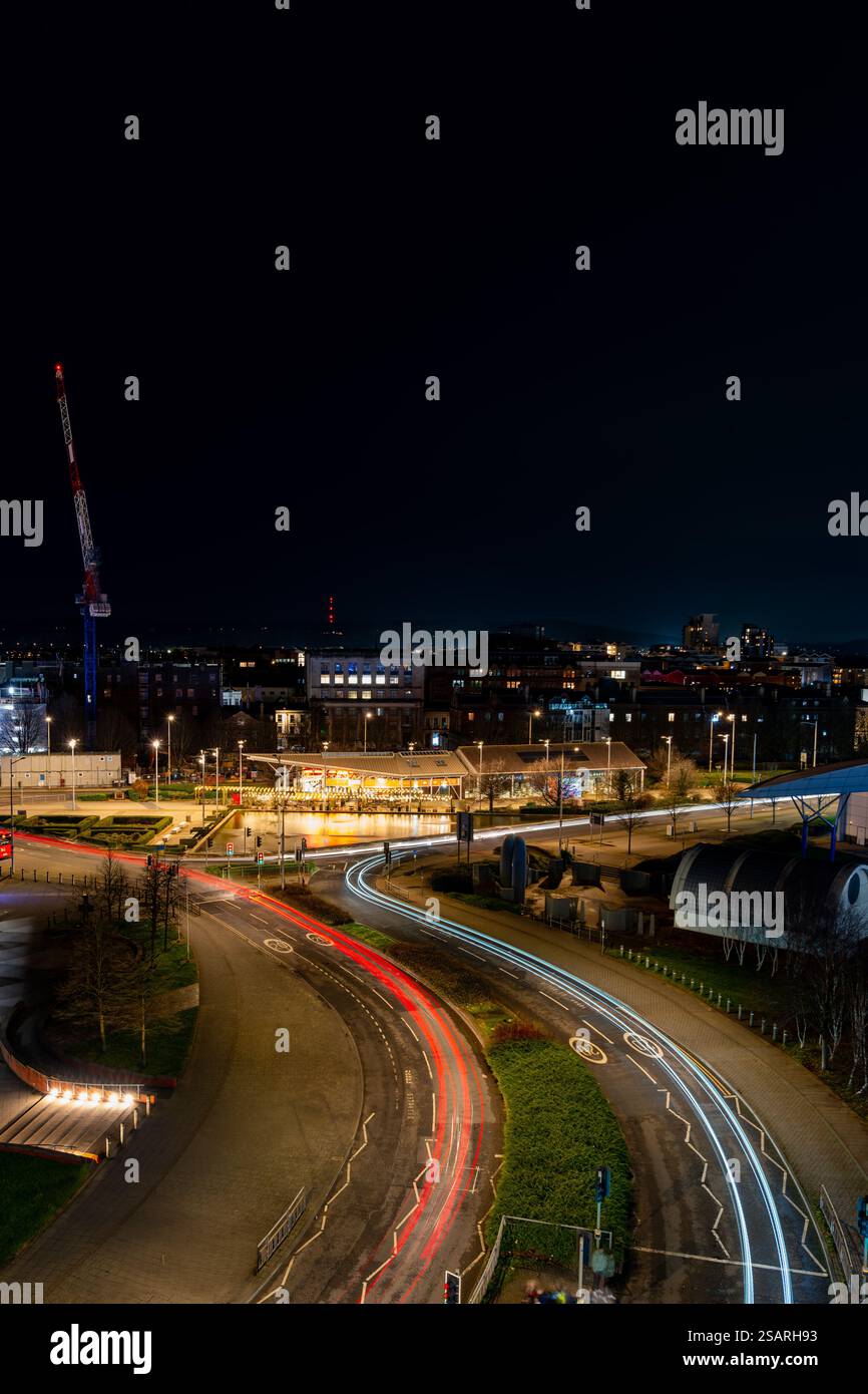 Vue aérienne du centre-ville de Cardiff la nuit, avec des sentiers lumineux de voitures et des bâtiments illuminés Banque D'Images