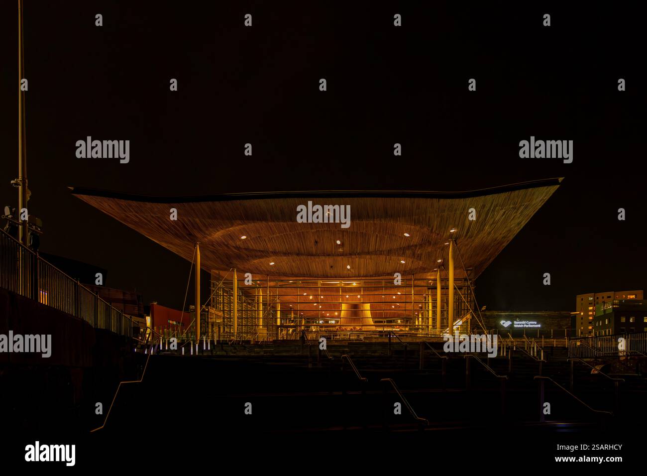 Le bâtiment Senedd, qui abrite le Parlement gallois, brille chaleureusement dans le ciel nocturne sombre du centre-ville de Cardiff Banque D'Images