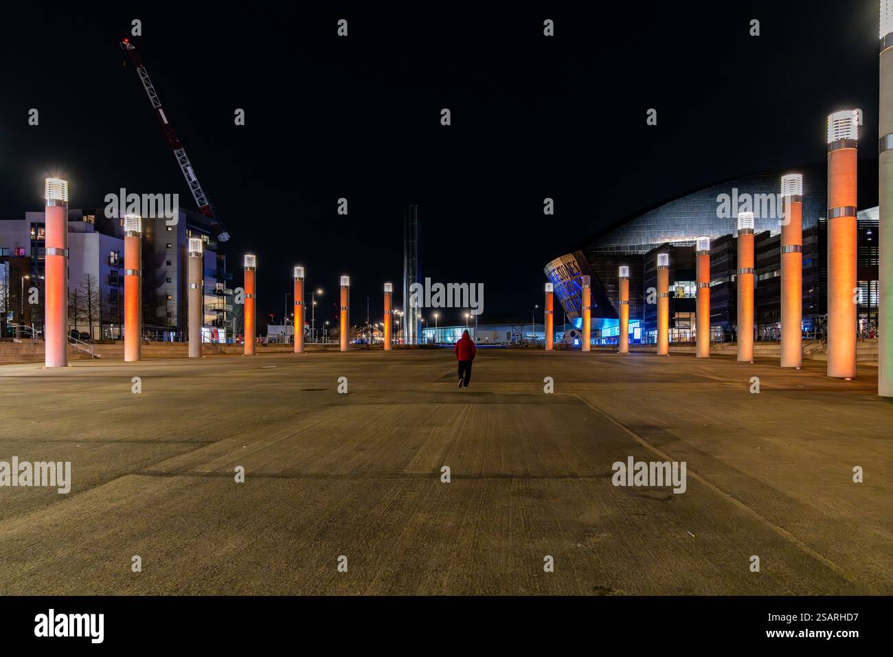 Touriste marchant à Roald Dahl Plass la nuit, avec le Wales Millennium Centre en arrière-plan, Cardiff, pays de Galles Banque D'Images