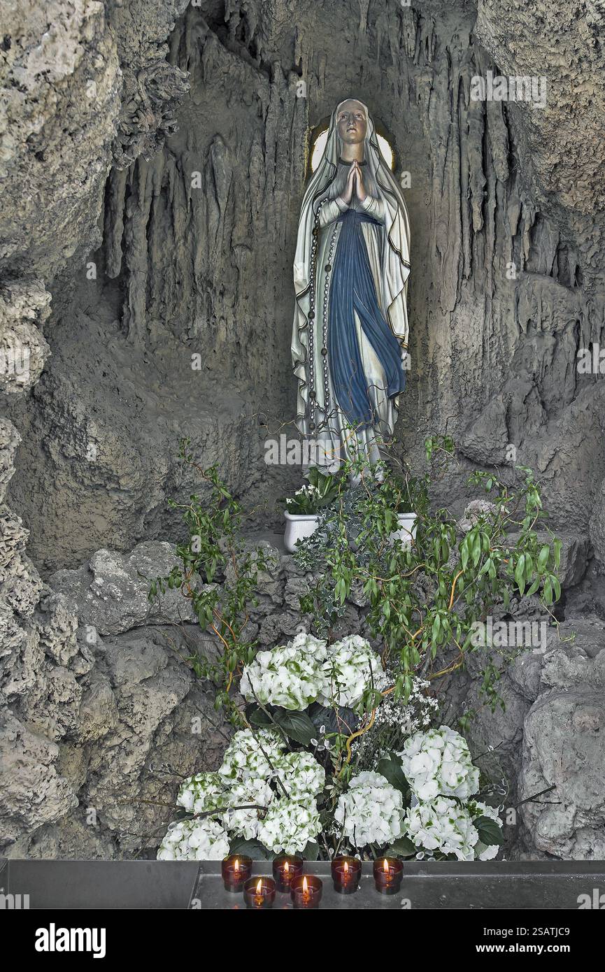 Figure de la Vierge Marie avec des décorations florales et des bougies sacrificielles dans la grotte de l'église paroissiale de St Laurentius, Koenigsdorf, Haut-Bava Banque D'Images