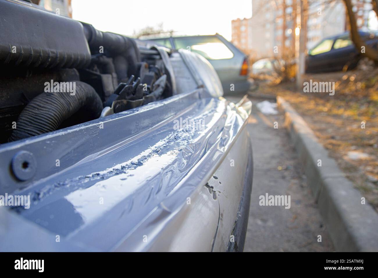 Capot de voiture ouvert révélant le moteur à la lumière du jour en milieu urbain Banque D'Images