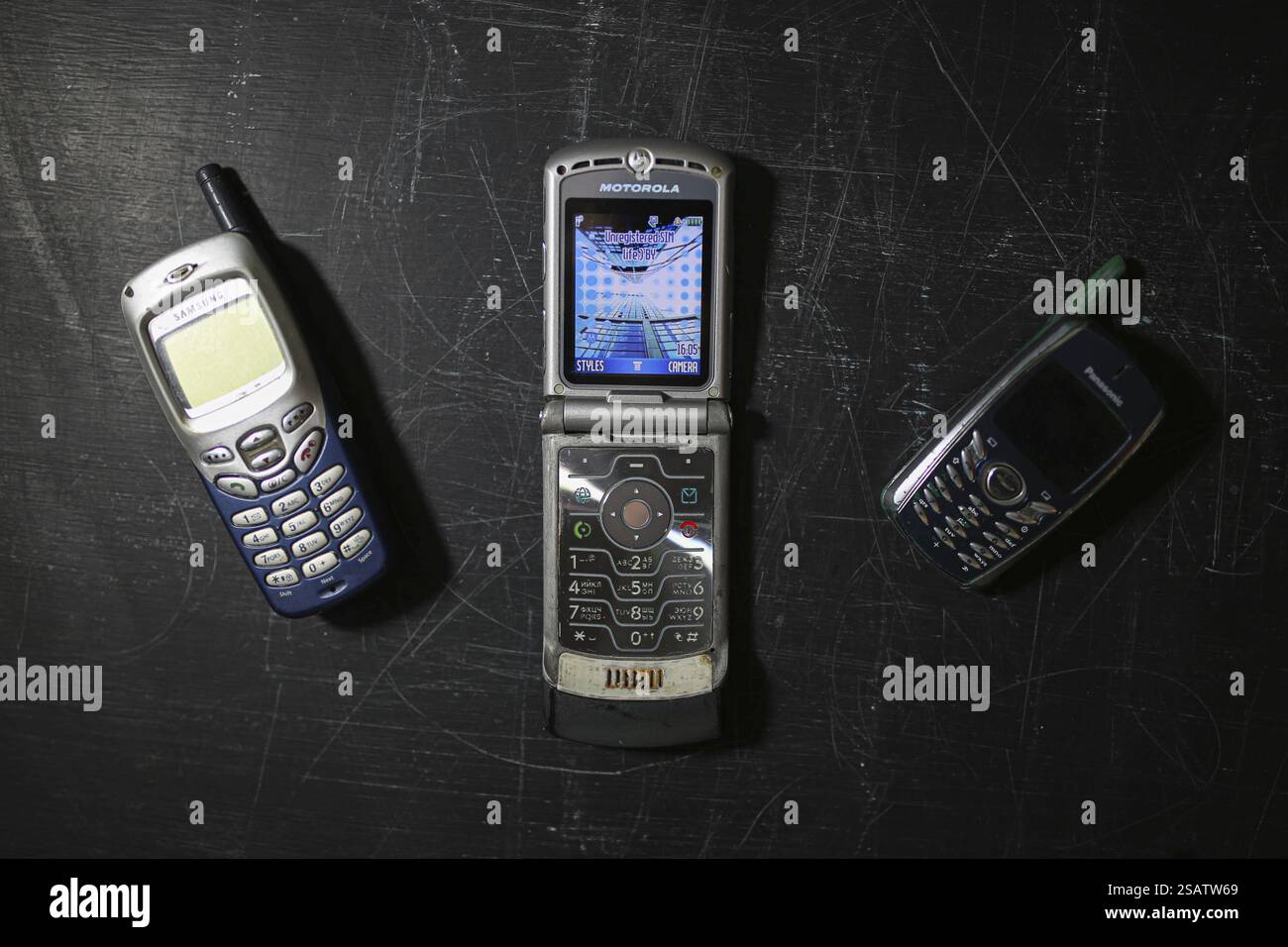 Trois téléphones cellulaires vintage affichés sur une surface rayée sombre Banque D'Images