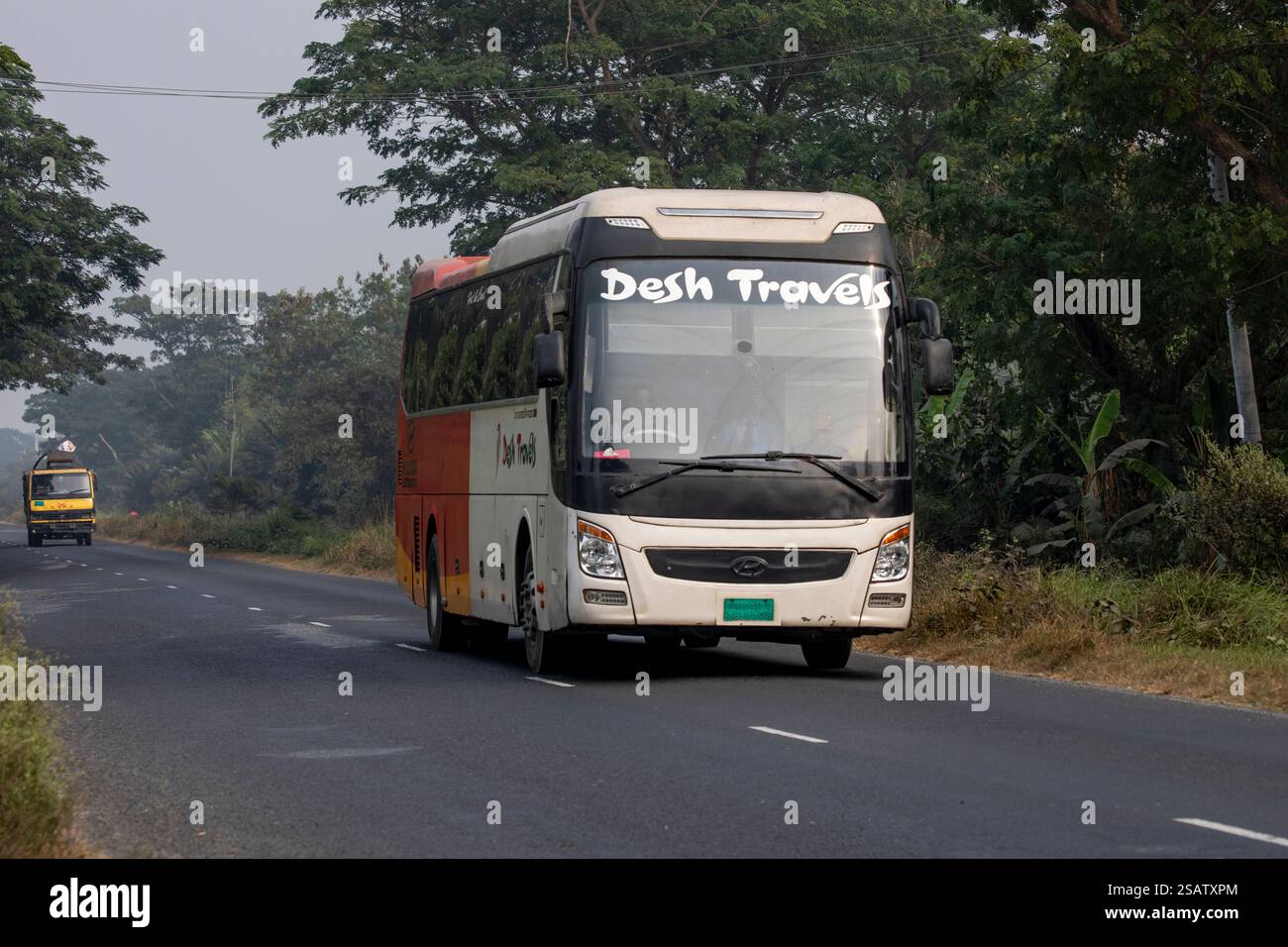 Un bus de luxe et un camion circulant le long de la route à Chalanbil, district de Pabna, Bangladesh. Banque D'Images Un bus de luxe et un camion circulant le long de la route à Chalanbil, district de Pabna, Bangladesh. Banque D'Images