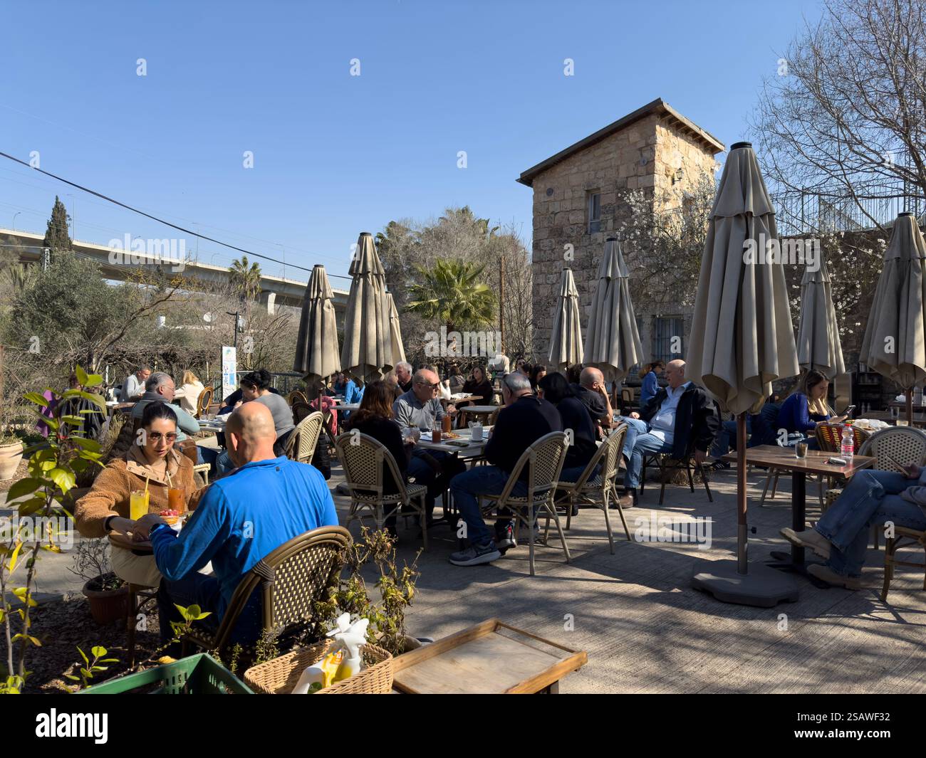Les gens sont assis dans le café Alloro situé dans la cour de Beit Yalin, la première maison construite par des Juifs dans une vallée de Jérusalem, qui sera plus tard appelée Emek Motza, un quartier à l'ouest de Jérusalem, en Israël. Banque D'Images