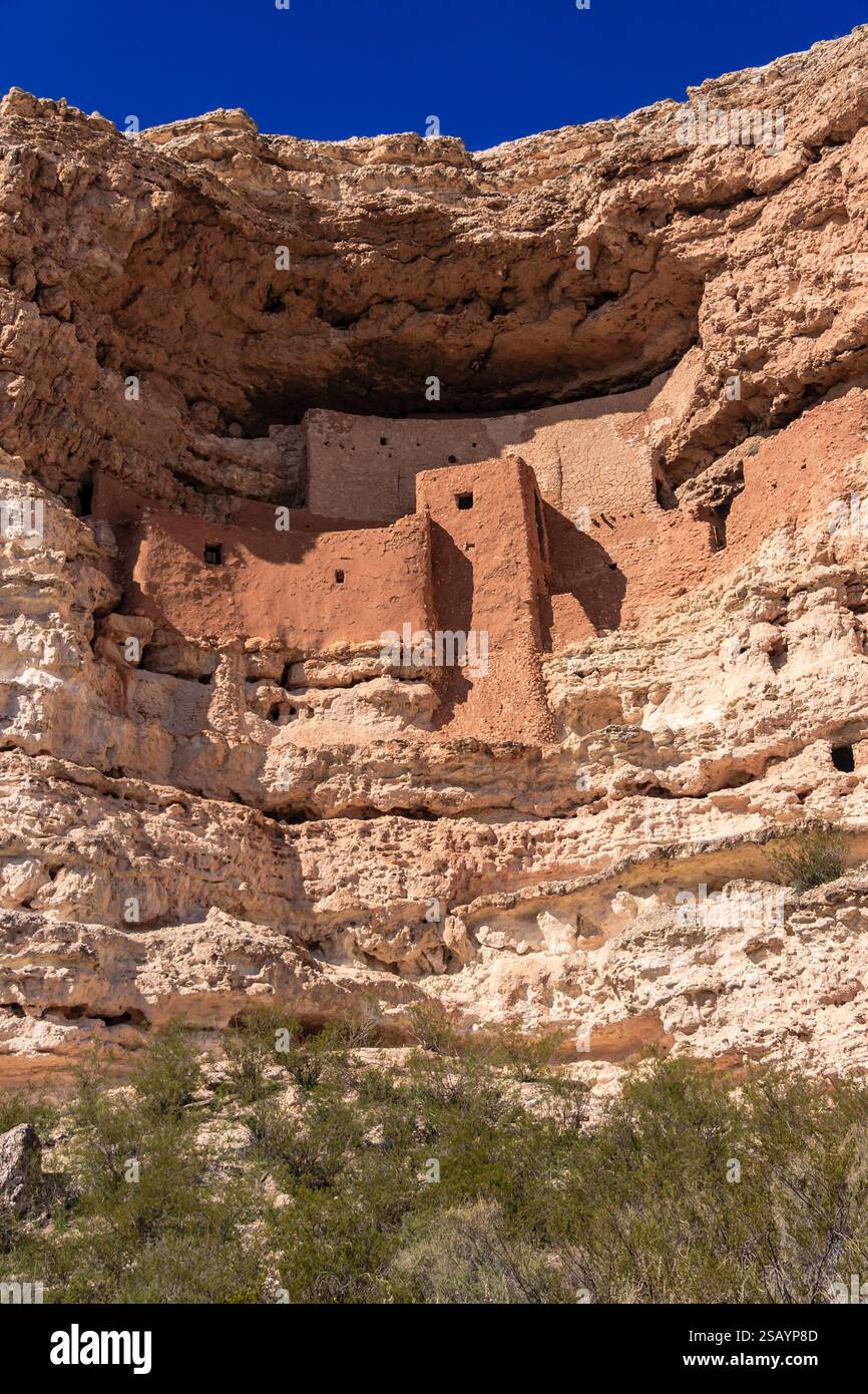 Une falaise rocheuse avec un bâtiment dessus. Le bâtiment est en pierre et a un toit incliné. La falaise est entourée d'un buisson vert Banque D'Images