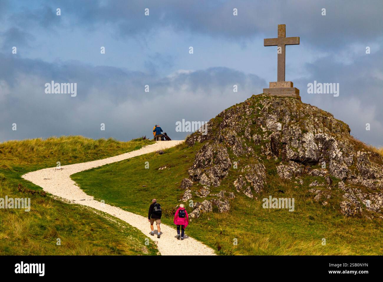 Touristes explorant le paysage vallonné avec croix à Ynys Llanddwyn une petite île au large de la côte d'Anglesey dans le nord du pays de Galles Royaume-Uni. Banque D'Images