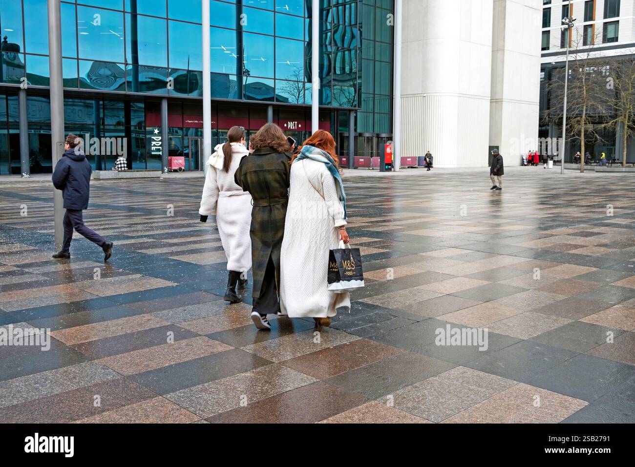 Vue arrière de personnes femmes faisant des achats sur Central Square devant la gare portant des manteaux d'hiver Cardiff City Centre Wales UK KATHY DEWITT Banque D'Images