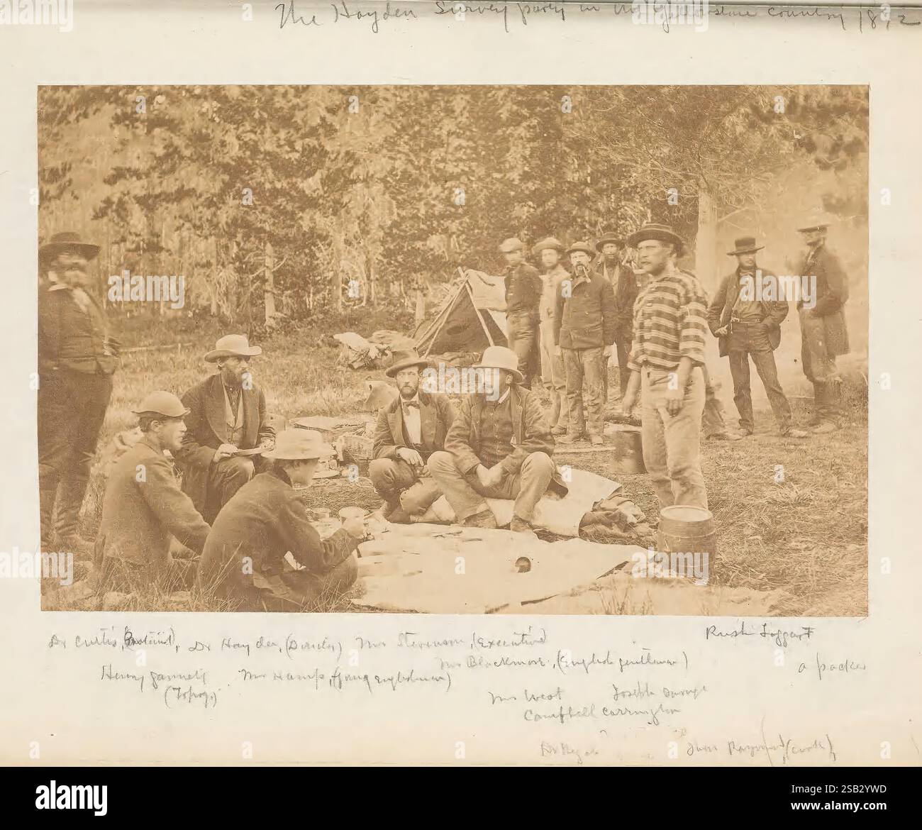 Aléatoire, enregistrements, de, a, durée de vie, 1846-1931, [en fait, 1932]., Un groupe d'individus est rassemblé dans une zone boisée, engagé dans une activité communautaire. Certains sont assis sur le sol, tandis que d'autres se tiennent à proximité, créant un sentiment de camaraderie. Divers articles, peut-être de la nourriture ou des fournitures, sont répartis devant eux, suggérant un pique-nique ou une réunion en plein air. Les environs présentent de grands arbres et des filtres solaires à travers le feuillage, améliorant l'atmosphère naturelle. Les participants semblent détendus et engagés dans la conversation, mettant en évidence un moment de loisirs et d'interaction sociale au milieu du natu Banque D'Images