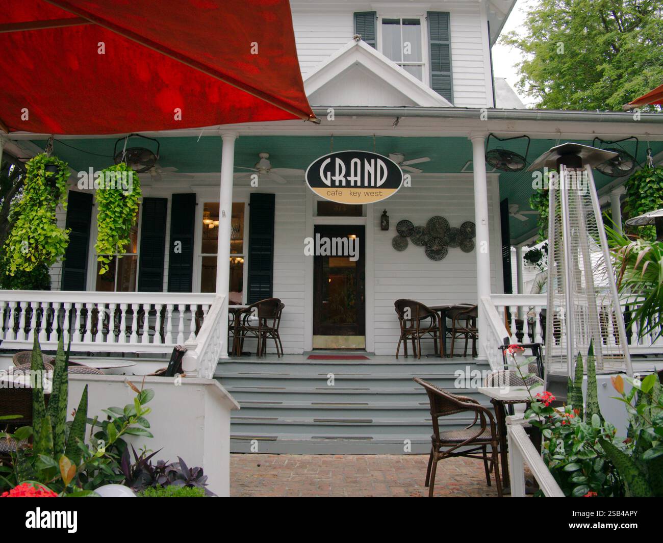 Le Grand Cafe mène au trottoir de la ligne principale au large porche blanc. Usage éditorial uniquement 22 janvier 2025, Key West, Floride, États-Unis. Chaises sur envelopper autour du porche Banque D'Images