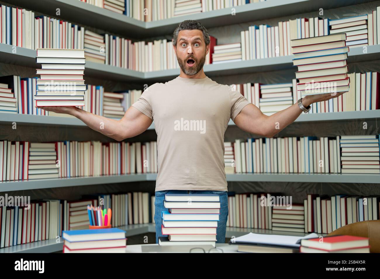Drôle d'enseignant de tenir beaucoup de livres. Professeur fou avec des livres. Enseignant enthousiaste dans la bibliothèque de livres de l'école. Examen universitaire. Étudier enseigner à l'université. Éducateur Banque D'Images