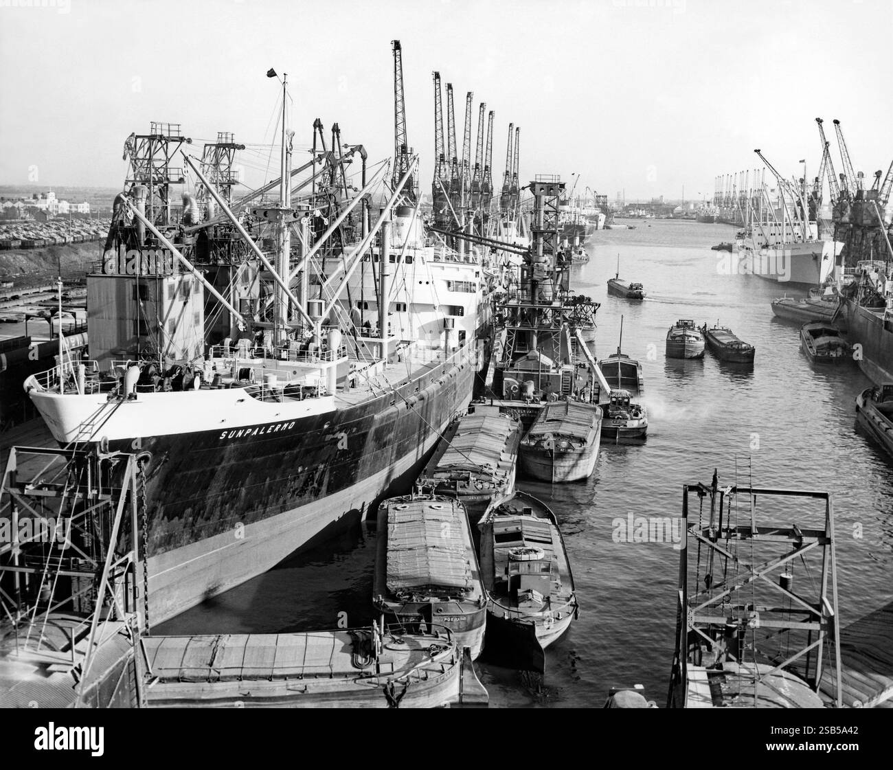 Une scène animée sur les quais, Port de Hull, Kingston upon Hull, East Yorkshire, Angleterre, Royaume-Uni en 1961. Ici, un cargo de construction italienne «Sunpalermo» décharge le grain dans des barges au moyen d’un élévateur à grain au quai numéro 1 à King George Dock. Le port de Hull est au confluent de la rivière Hull et de l'estuaire Humber. Les grandes barges à front plat et larges étaient à l'origine connues sous le nom de «quilles Humber». Banque D'Images