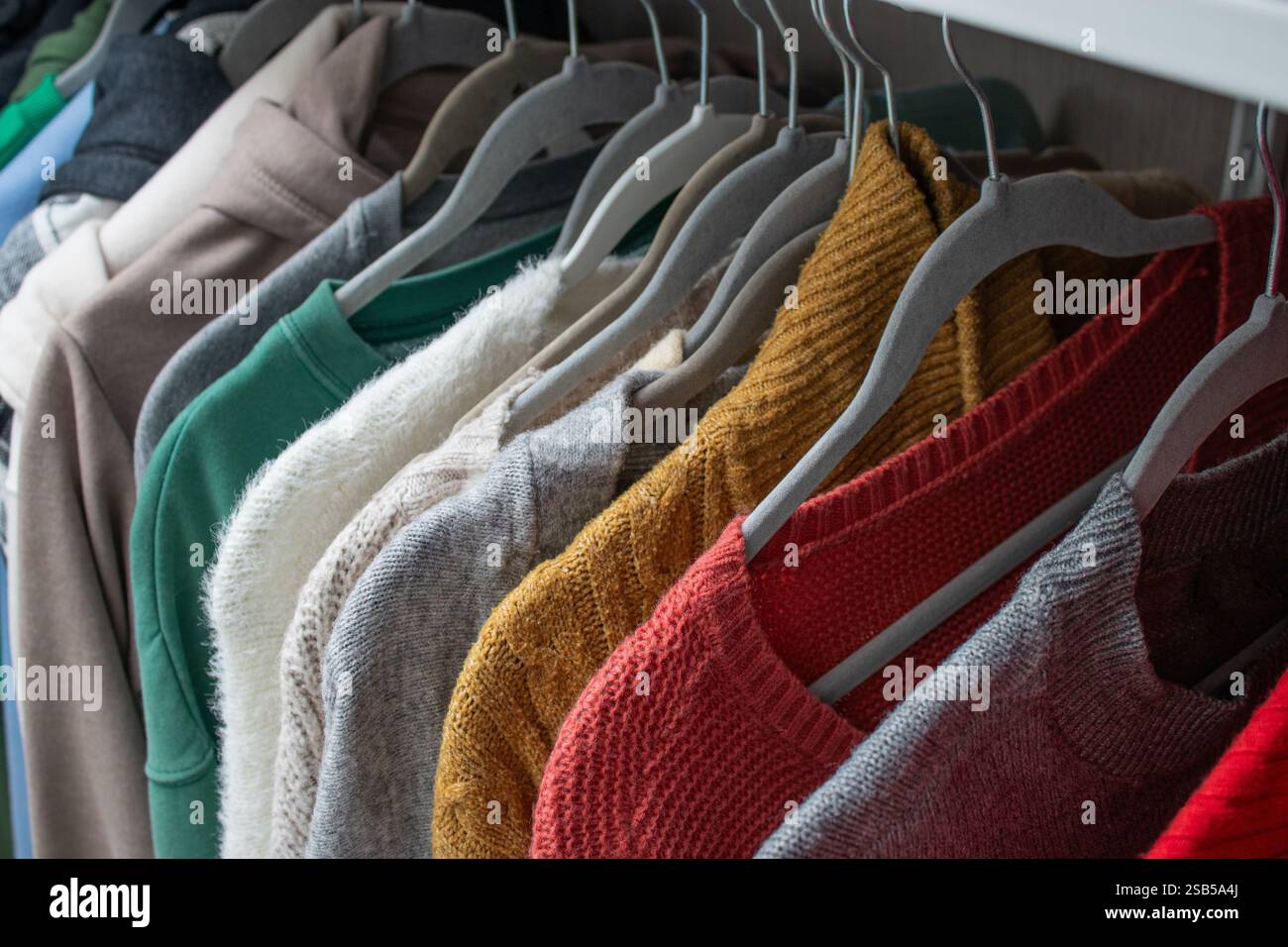 Gros plan de vêtements tricotés chauds féminins sur des cintres dans le placard Banque D'Images