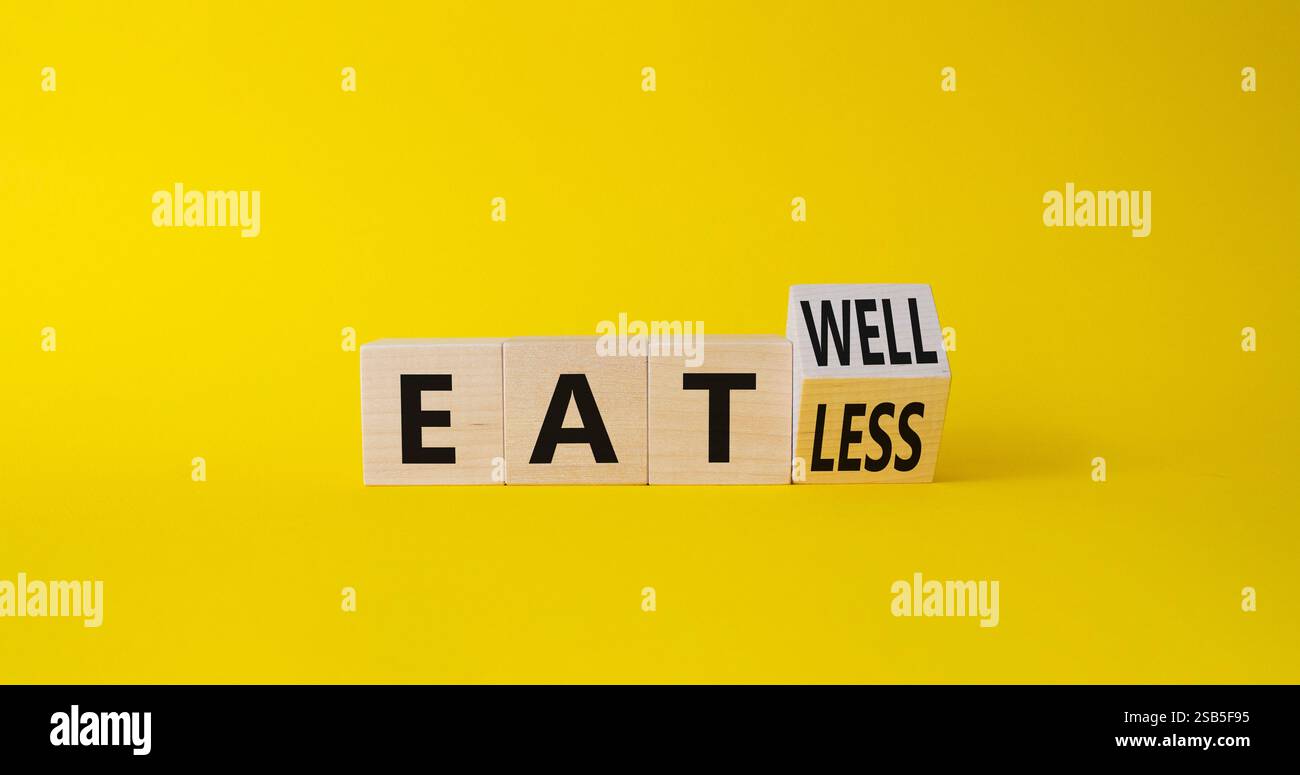 Manger moins que manger bien symbole. Cube en bois tourné avec des mots manger moins vs manger bien. Beau fond jaune. Psychologie concept médical. Copier l'espace Banque D'Images