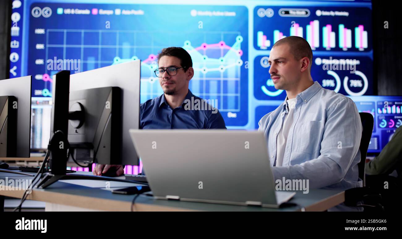 Homme afro-américain surveille le tableau de bord au centre de données pour analyse. Le technicien contrôle le serveur dans le bureau pour la surveillance de la veille stratégique. Banque D'Images