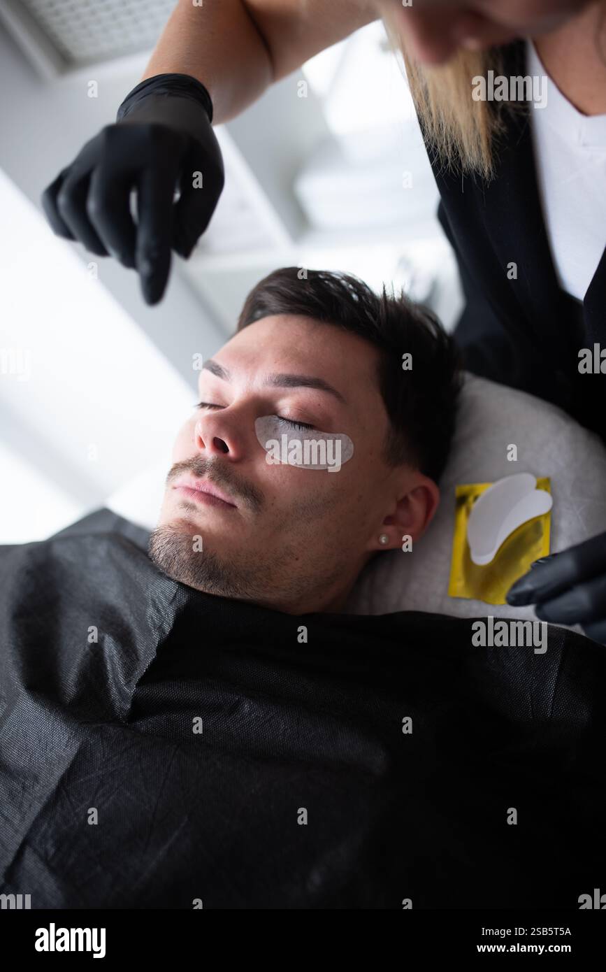Un jeune homme dans un salon de beauté prenant soin des cils. Banque D'Images